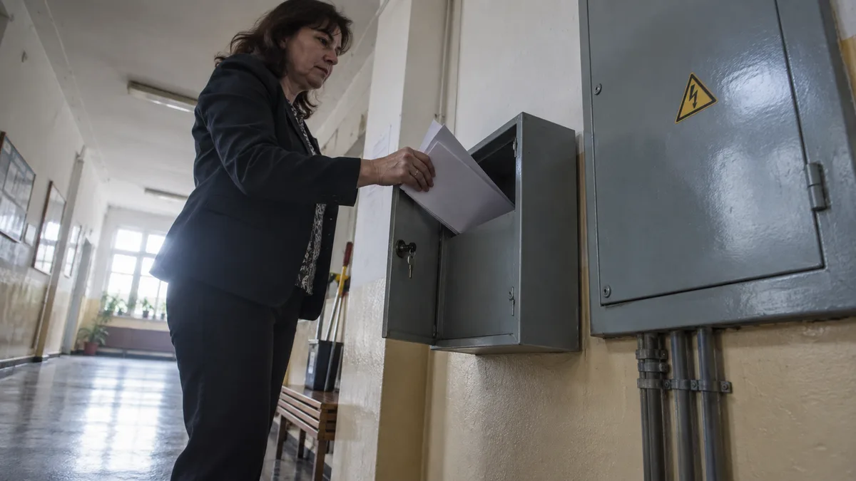Chodba školní budovy s rozvaděčem v nástěnné skříni, vedle něj deska s revizními zprávami a plánem kontrol.